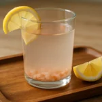 Glass of pink salt water with lemon, showing the salt trick in a natural home setting.