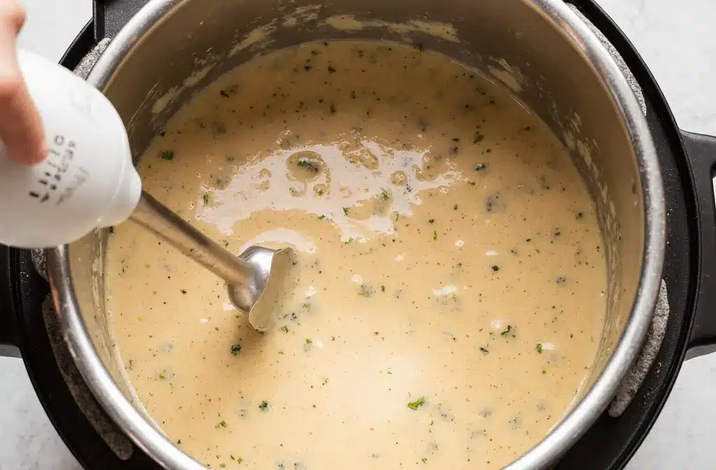 Creating-Creamy-Texture-by-Blending Immersion blender blending creamy vegetable soup in pot.