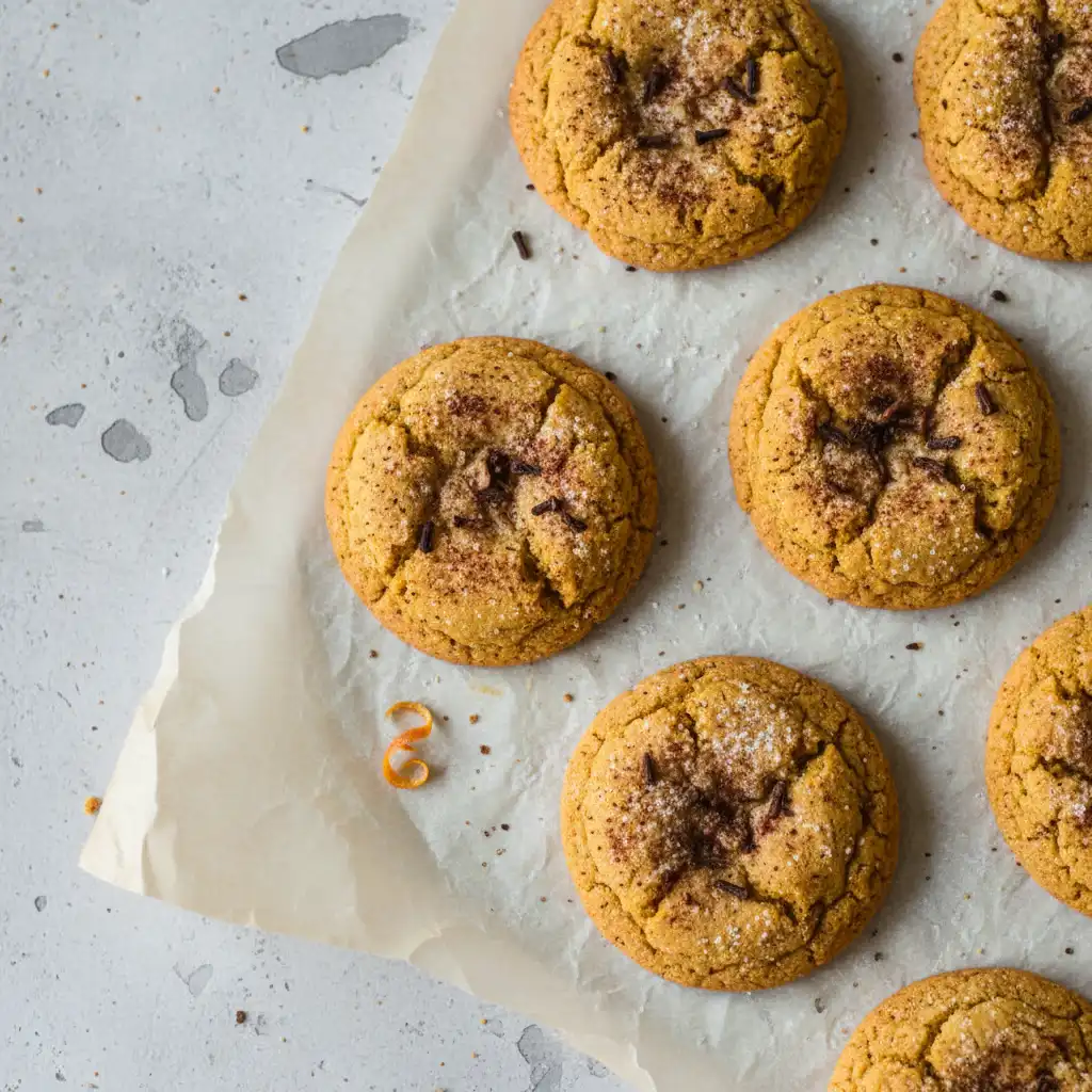 Freshly baked pumpkin spice cookies with golden edges on parchment paper