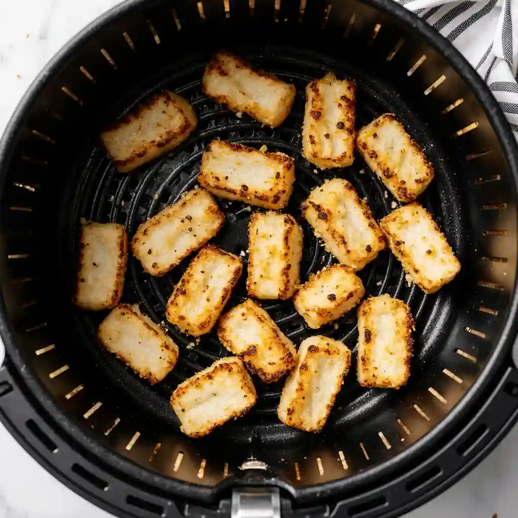 The Secret Trick for Insanely Crispy Halloumi Fries Drenched in Hot Honey 2 Crispy halloumi fries cooked to golden perfection in an air fryer basket.