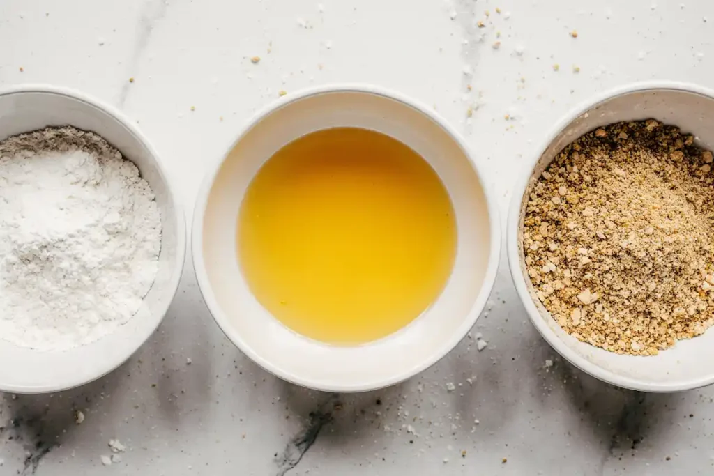Hot honey feta chicken recipe breading process with flour, egg, and panko breadcrumbs in bowls