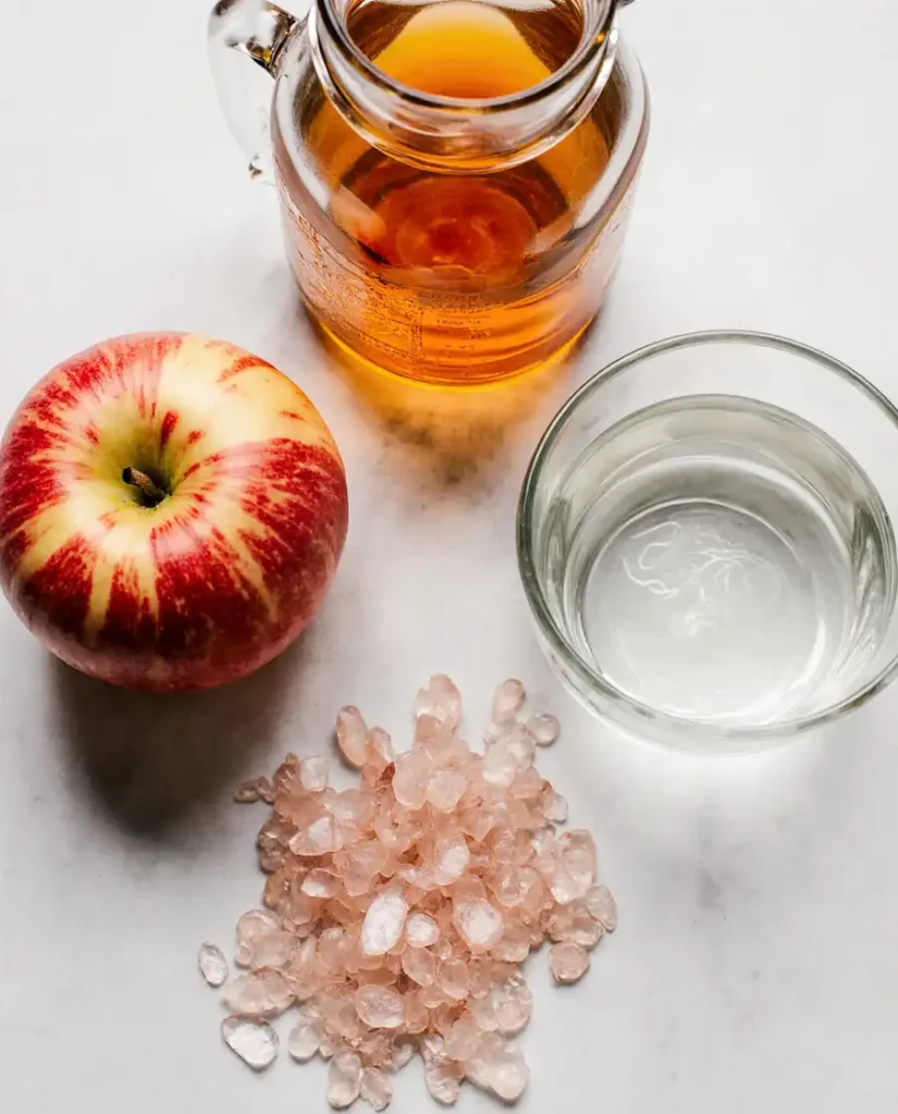 Ingredients for making pink salt and apple cider vinegar drink including raw ACV and Himalayan salt